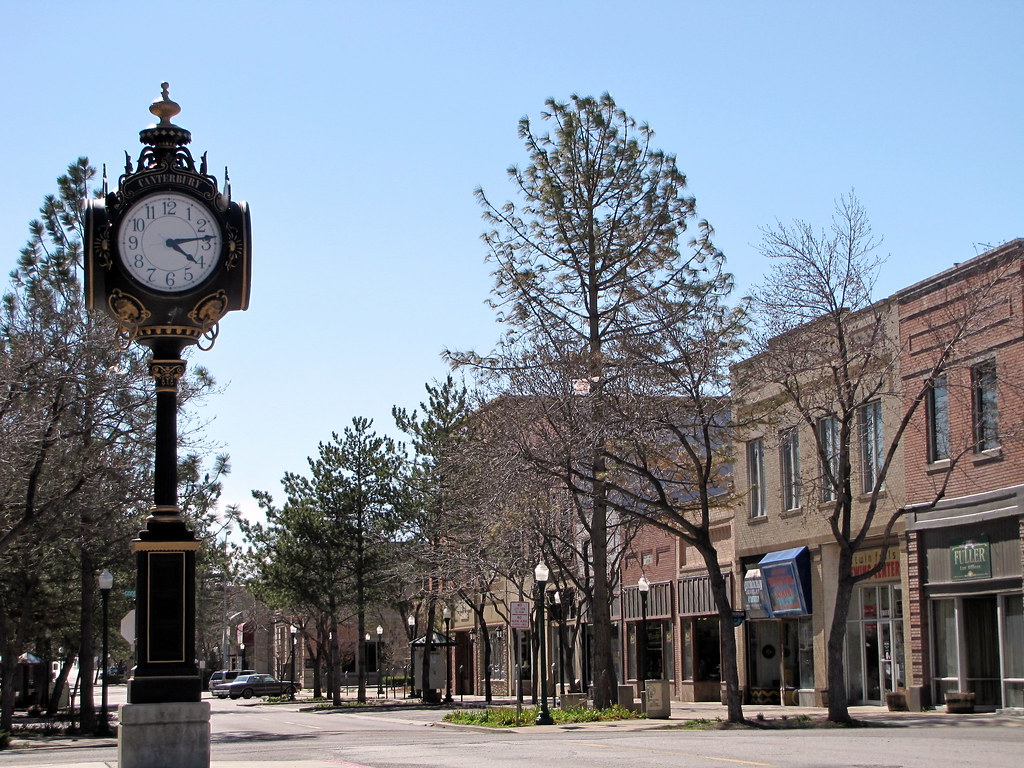 A clock on a pole in front of a building.