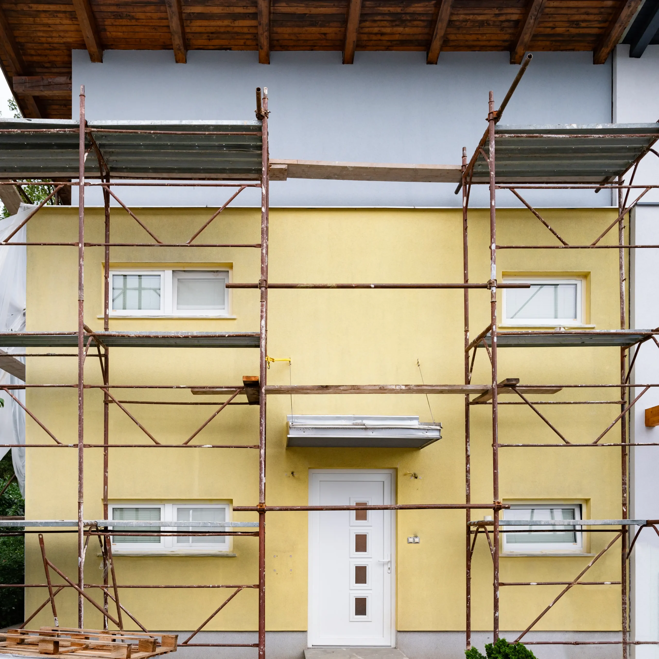 A yellow house with a metal scaffolding in front of it.